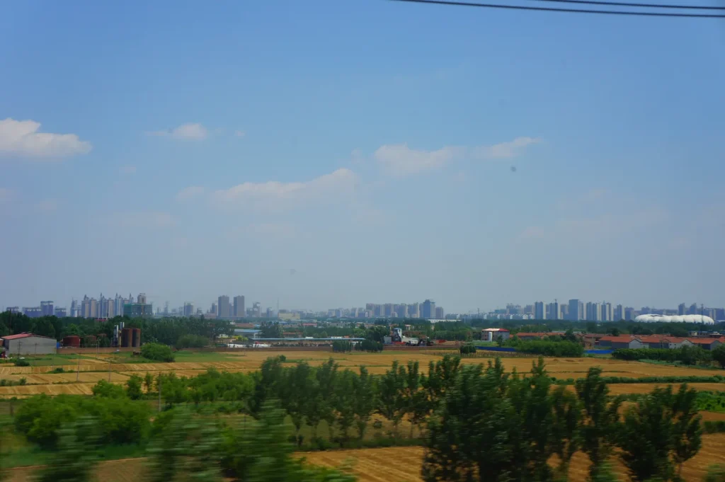 Cangzhou city skyline and fields seen from a train route