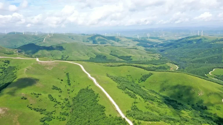 Aerial view of green hills, grassland roads and wind turbines in Fengning Bashang Grassland