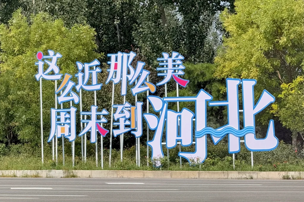 A public sign showing Hebei tourism slogan in Chinese, often translated as So Close, So Beautiful, Spend Your Weekend in Hebei