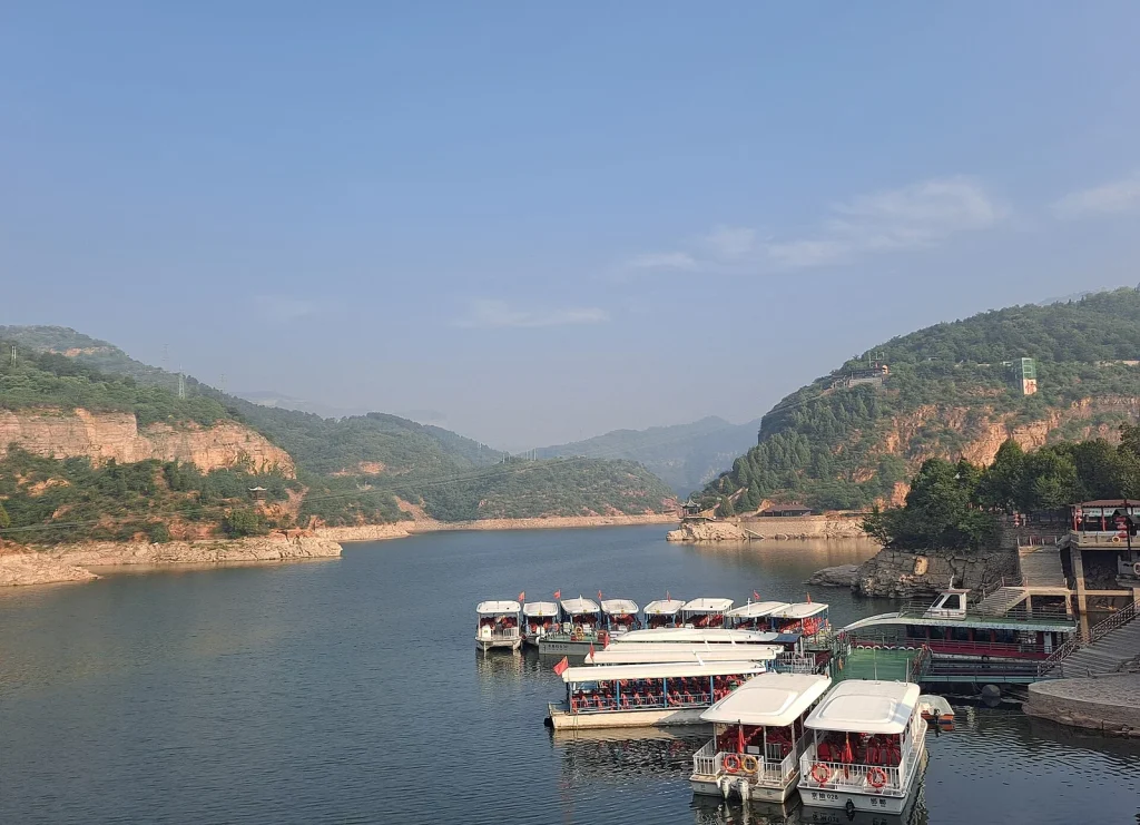 Sightseeing boats at a Jingniang Lake dock beneath Taihang cliffs