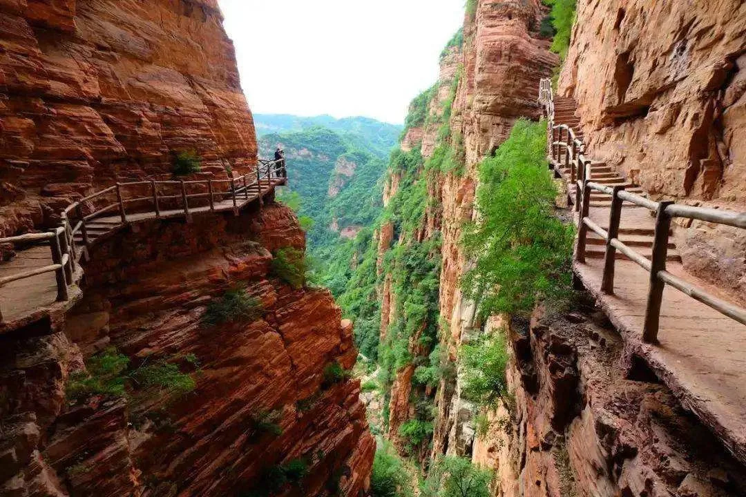 Cliffside walkway between red sandstone walls at Xingtai Grand Canyon