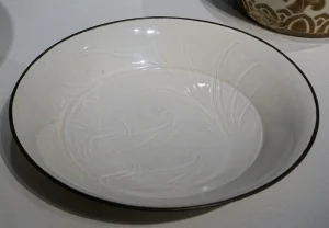 Northern Song Ding ware dish with incised ducks, attributed to the Quyang Ding kilns, photographed in a museum display