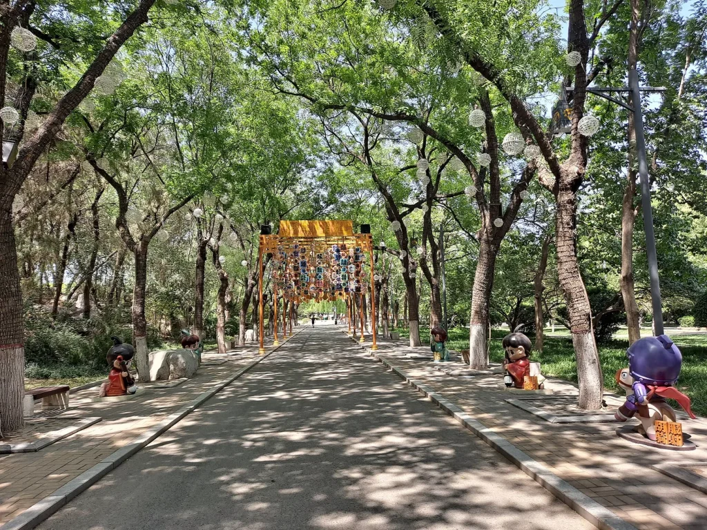Shaded path with cultural installations inside Congtai Park