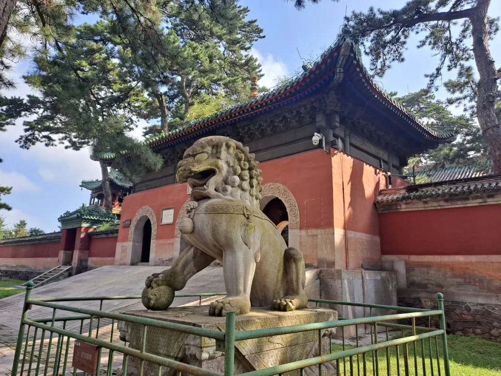 Stone guardian in front of the red entrance building at Pule Temple, Chengde