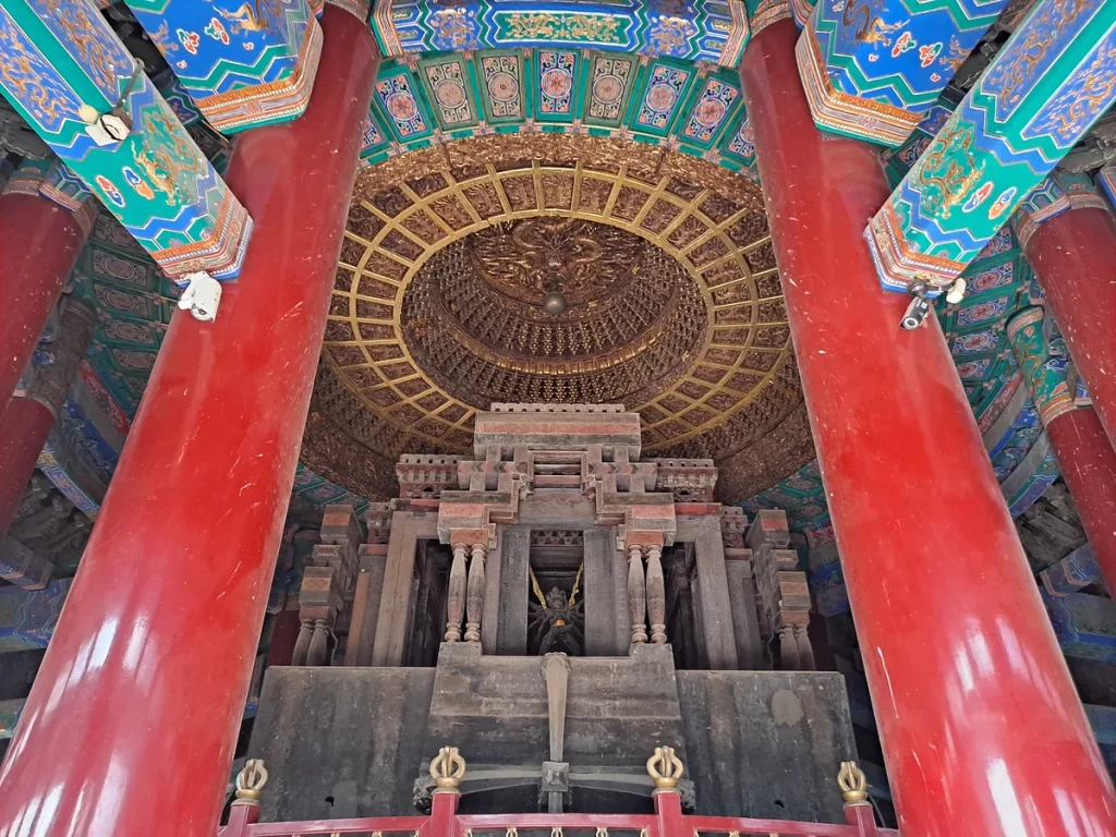 Red columns, painted beams and a gilded circular caisson inside Xuguang Pavilion at Pule Temple
