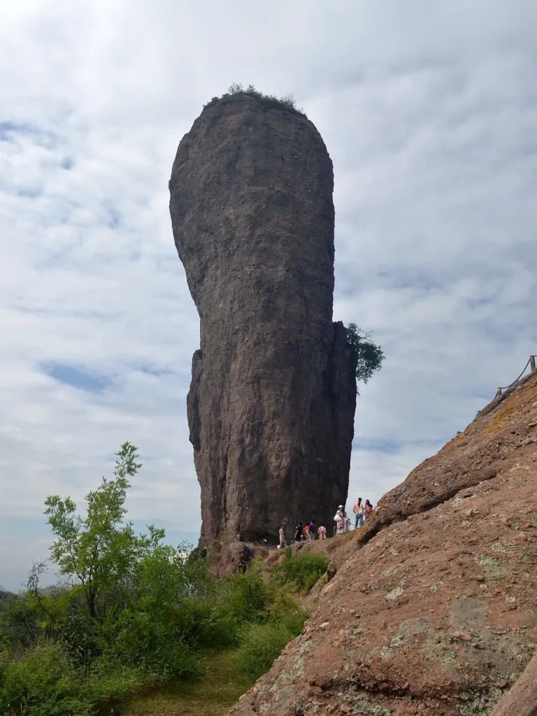Visitors standing below the tall Qingchui Peak rock pillar